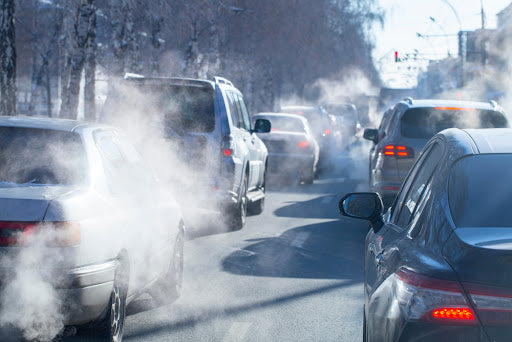 A lot of cars with smoke are shown polluting the air