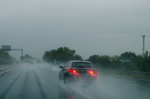 A car is moving in rainy weather on a wet road.